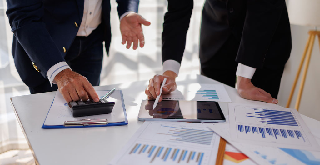 Vue en plongée sur une grille de comparaison de simulations de crédit immobilier en cours de remplissage manuel, entourée de documents de simulation sur un bureau organisé